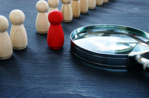 Identify concept. Recruitment and talent management. Red figurine and magnifier.